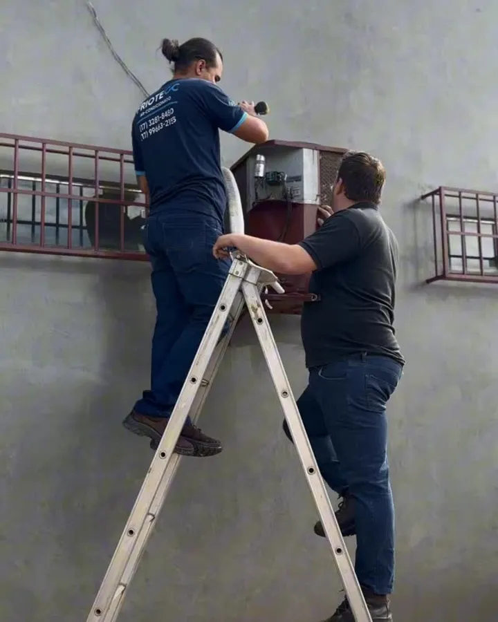 Técnico da Friotecc no alto da escada fazendo manutenção de ar condicionado
